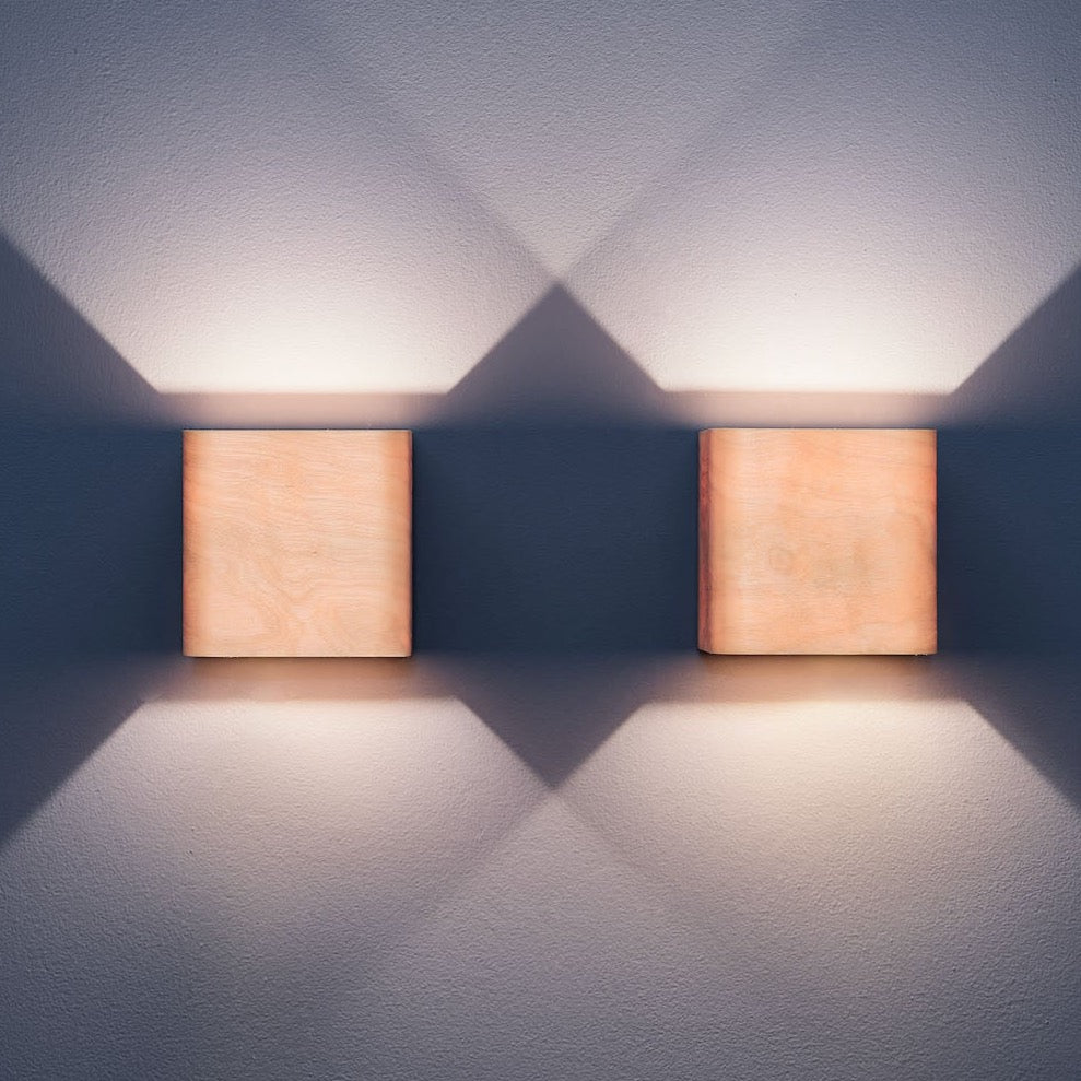Pair of birch bedside wall lamps mounted by a bed